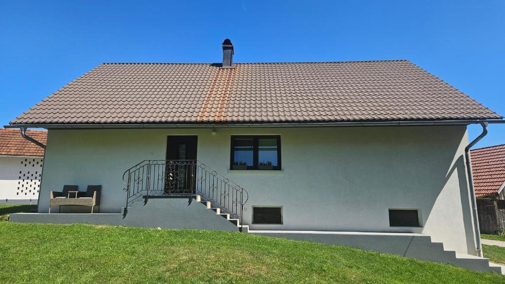 a white house with a staircase and a roof at Francek house Podčetrtek in Buče