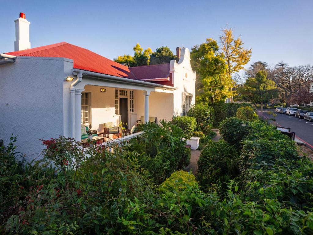 a white house with a red roof at Boschhuis Apartments - Stellenbosch in Stellenbosch