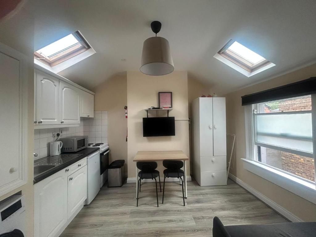 a kitchen with white cabinets and a table and stools at Charming 1Bed Flat In Dublin Sleeps 2 in Dublin