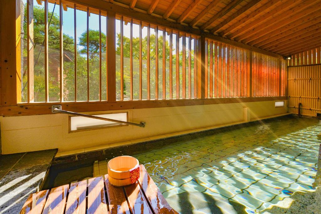 a swimming pool in a building with a window at Ooedo Onsen Monogatari Hotel Shinko in Fuefuki
