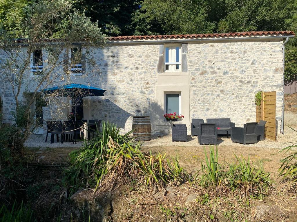 a stone house with chairs and a table in front of it at les rives du Lay gîte Joly in Le Boupère