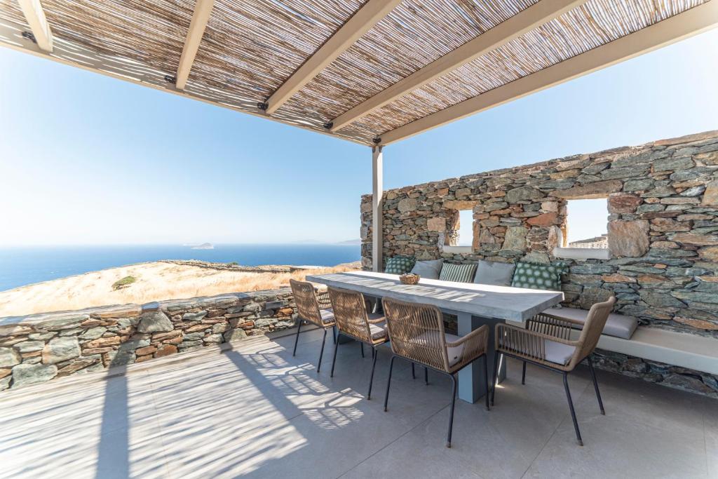 a patio with a table and chairs and the ocean at Ayelma - Kythnos Villa in Kithnos