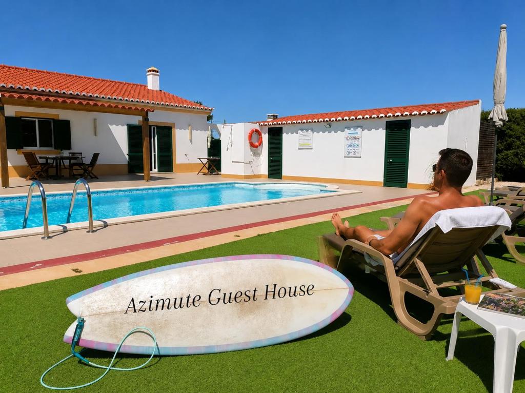 a man sitting in a chair next to a surfboard at Azimute Guest House in Aljezur