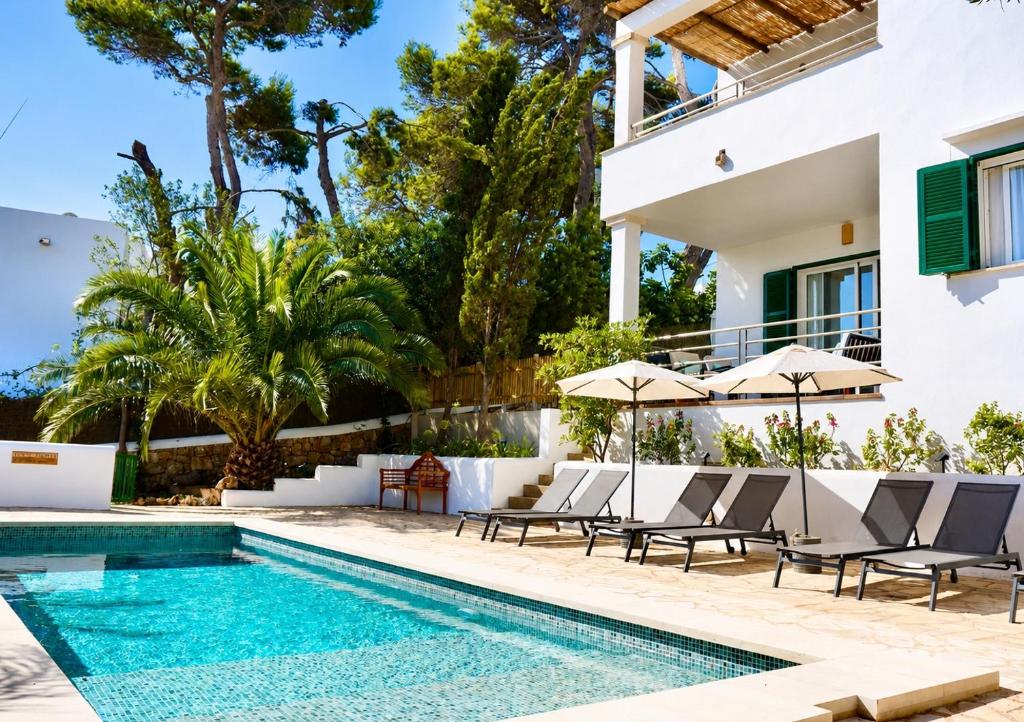 a villa with a swimming pool with chairs and umbrellas at Villa Riviera in Cala d´Or