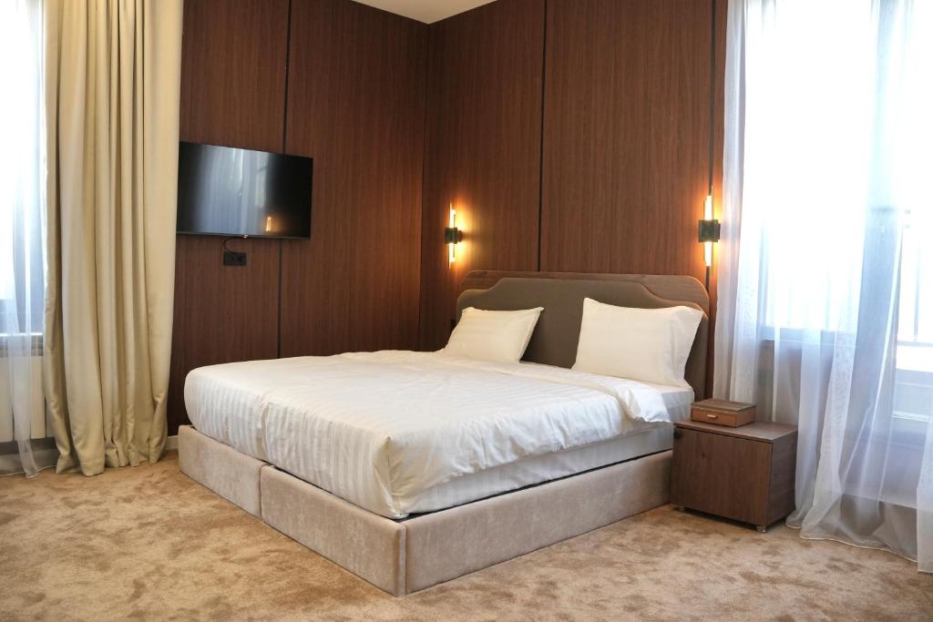 a bedroom with a bed with a television on the wall at Monteva Boutique Hotel in Almaty