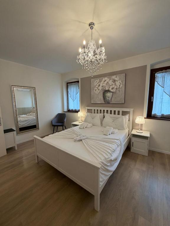 a bedroom with a large white bed and a chandelier at Sottocastello 1 in Gorizia