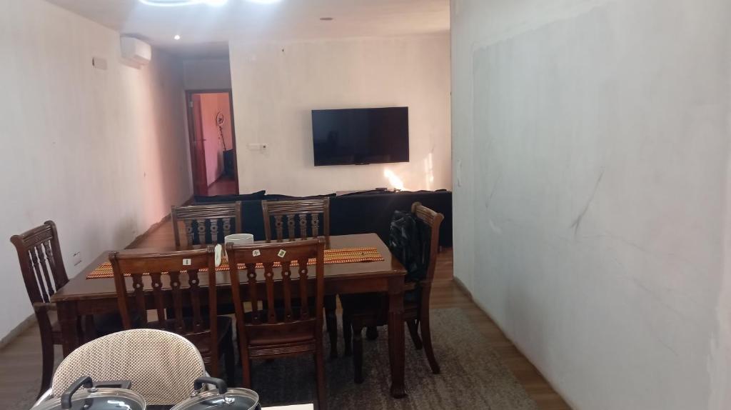 a dining room with a table and chairs and a television at Pati place in Mememo