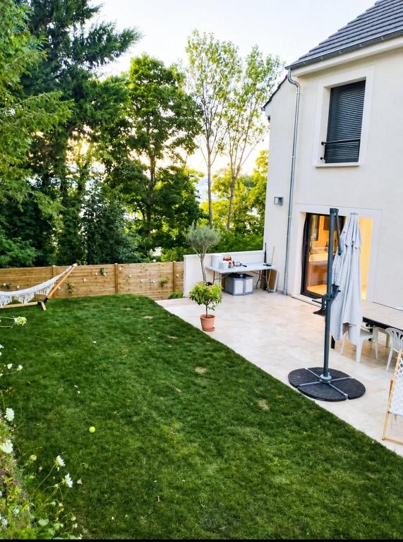 a backyard with a lawn and a white house at House in Clamart