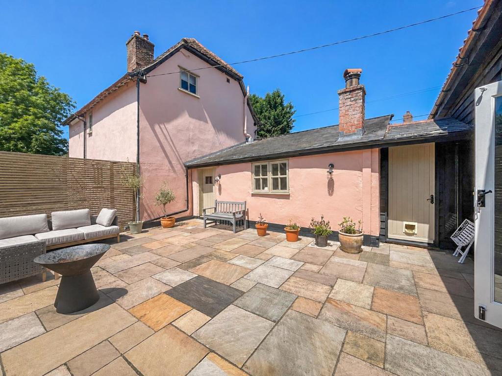 a patio with a couch and a house at The Cottage in Chelsworth
