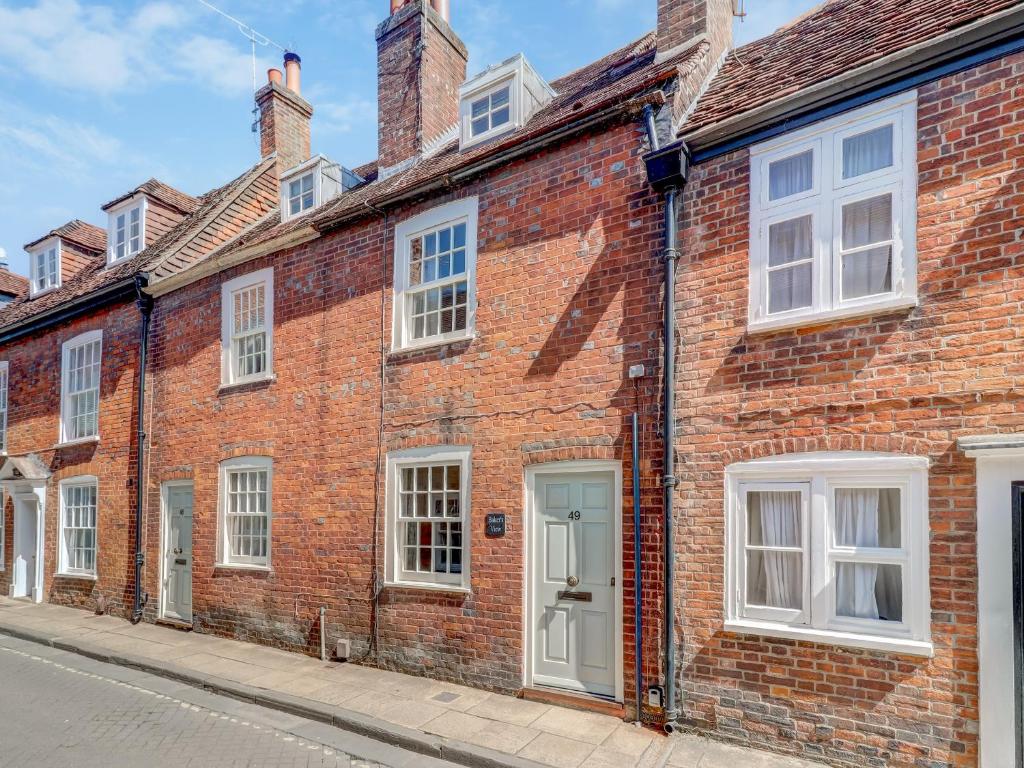 a red brick house with white windows on a street at Bakers View in Winchester