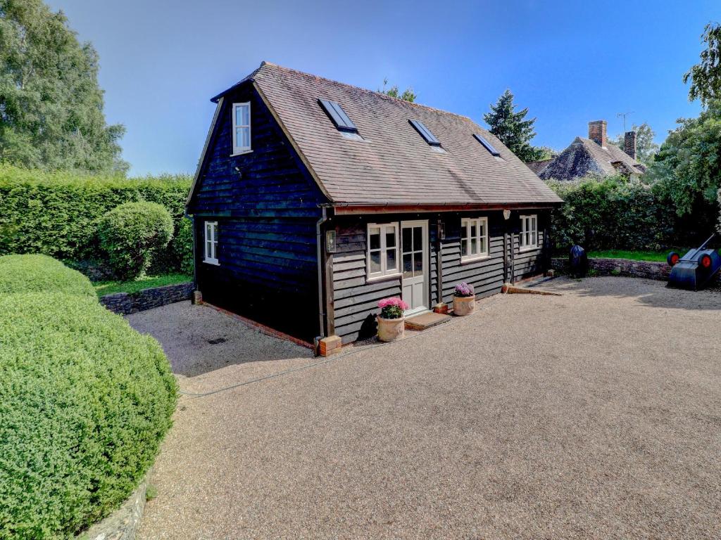 a small house with a roof on a driveway at Meadow Barn in Pulborough