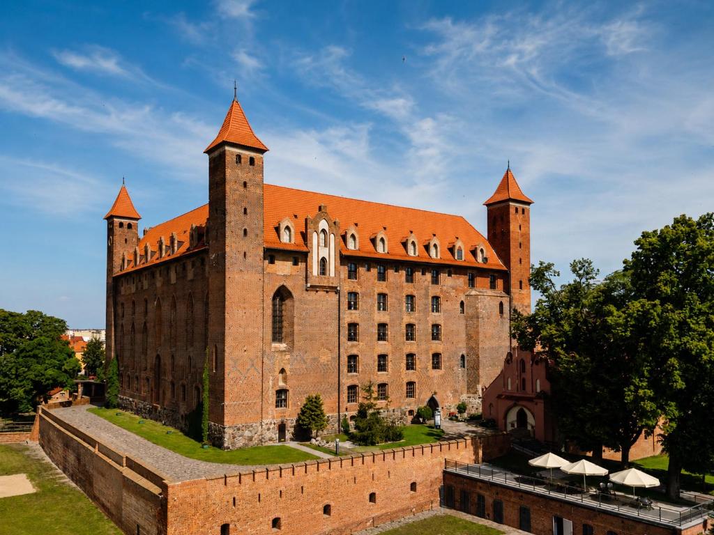 a large brick building with a red roof at Hotel Zamek Gniew in Gniew