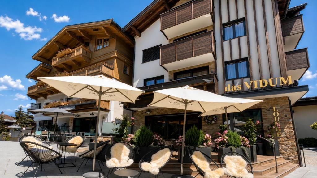 a restaurant with chairs and umbrellas in front of a building at Appartementhaus Das Vidum in Söll