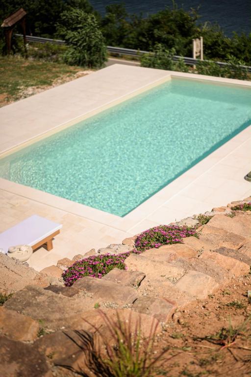 a swimming pool with a bench next to a stone wall at Dream Tricule in Sviniţa