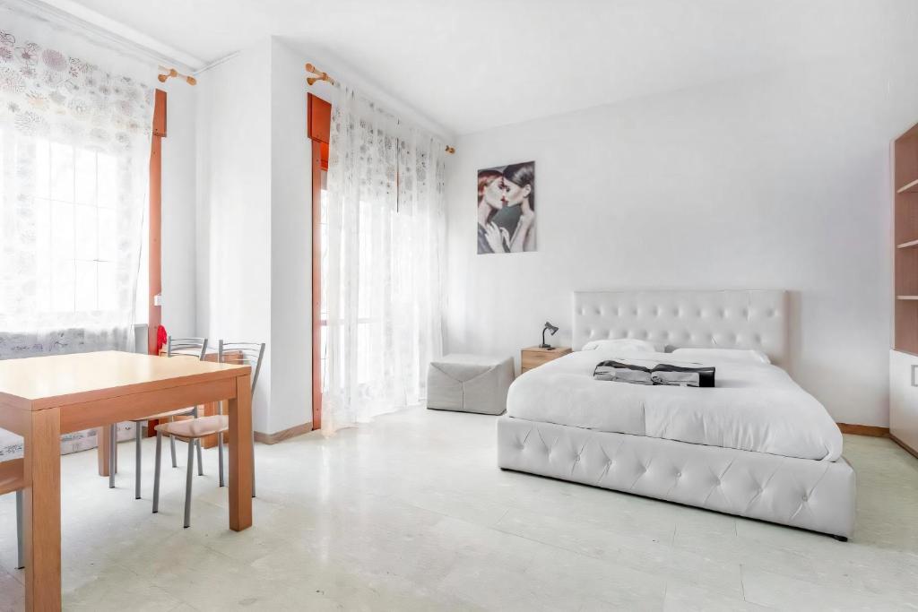 a white bedroom with a white bed and a desk at Moncler House Navigli in Milan