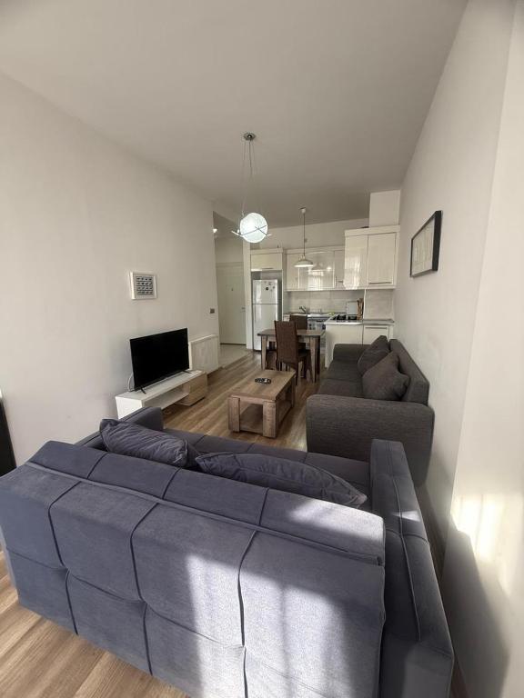 a living room with a blue couch and a kitchen at Apartment in green Budapest in Tbilisi City