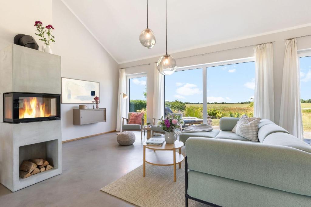 a living room with a couch and a fireplace at Feldkoje - Luxuriöses Design-Ferienhaus mit Kamin und Feldrandlage in Fehmarn