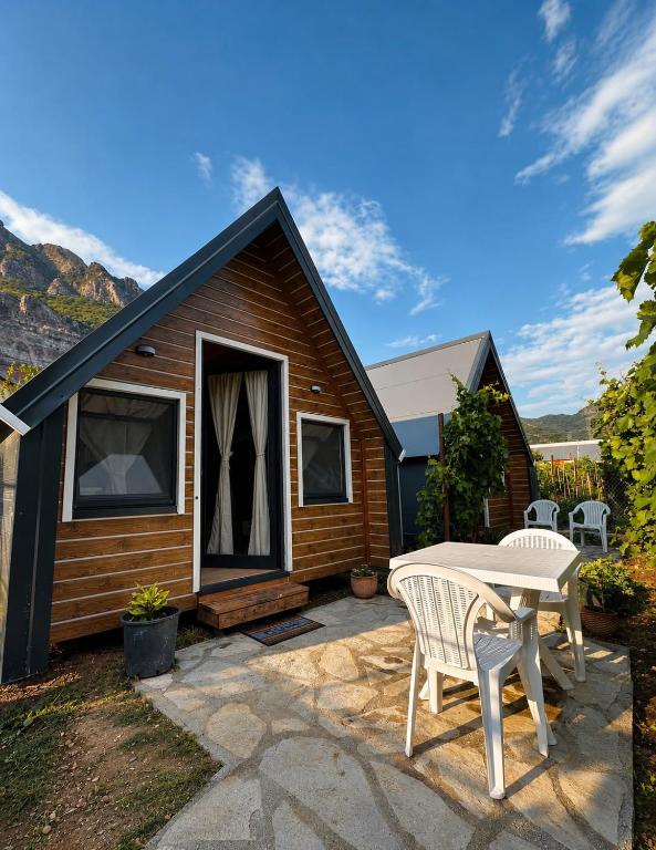 a small house with a patio and a table at Koman Twin Cabins in Gushtë