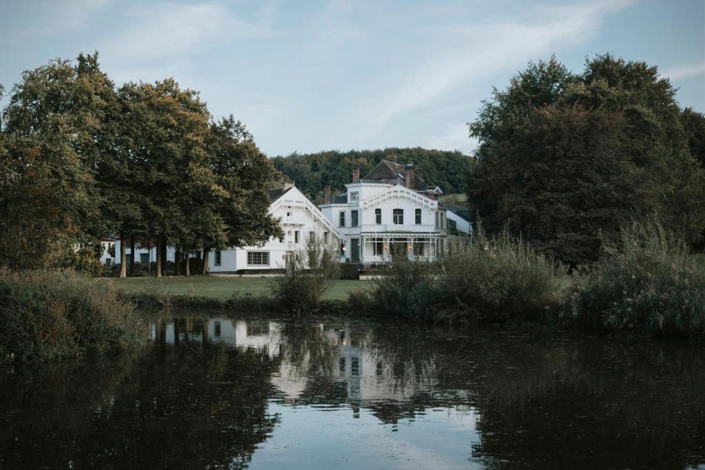 a large white house with a pond in front of it at Landgoed Altenbroek in Voeren