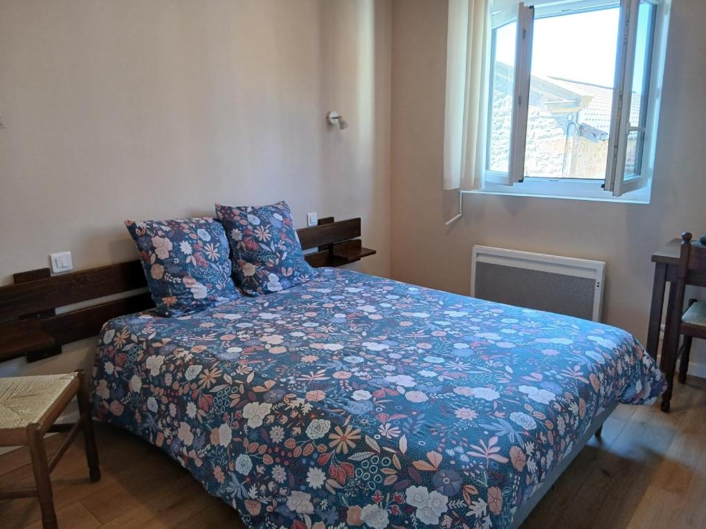 a bedroom with a bed with a blue comforter and a window at Hôtel de Cenves in Cenves