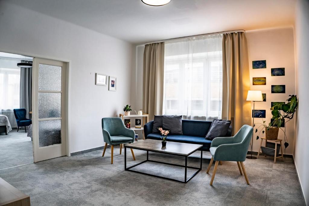 a living room with a blue couch and chairs at Petit Dependance in Bratislava