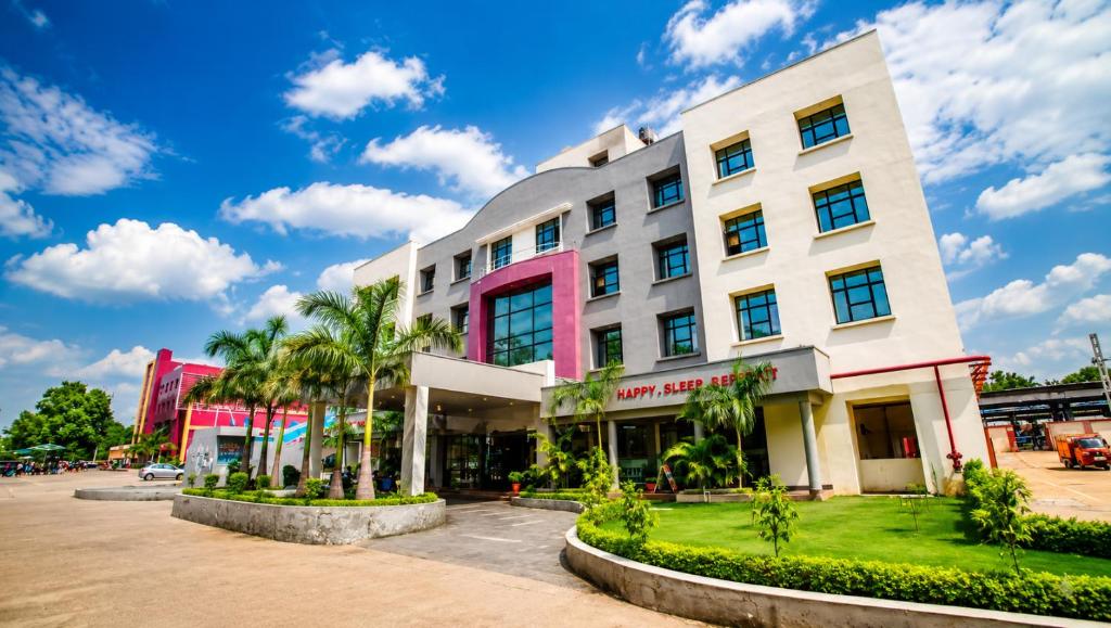 ein Gebäude mit Palmen davor in der Unterkunft Max Hotels Jabalpur in Jabalpur