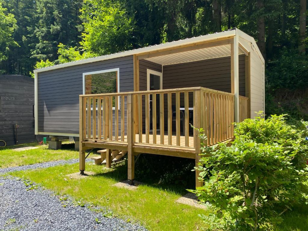 a tiny house with a deck in the grass at Camping Héiltzerstee in Rambrouch