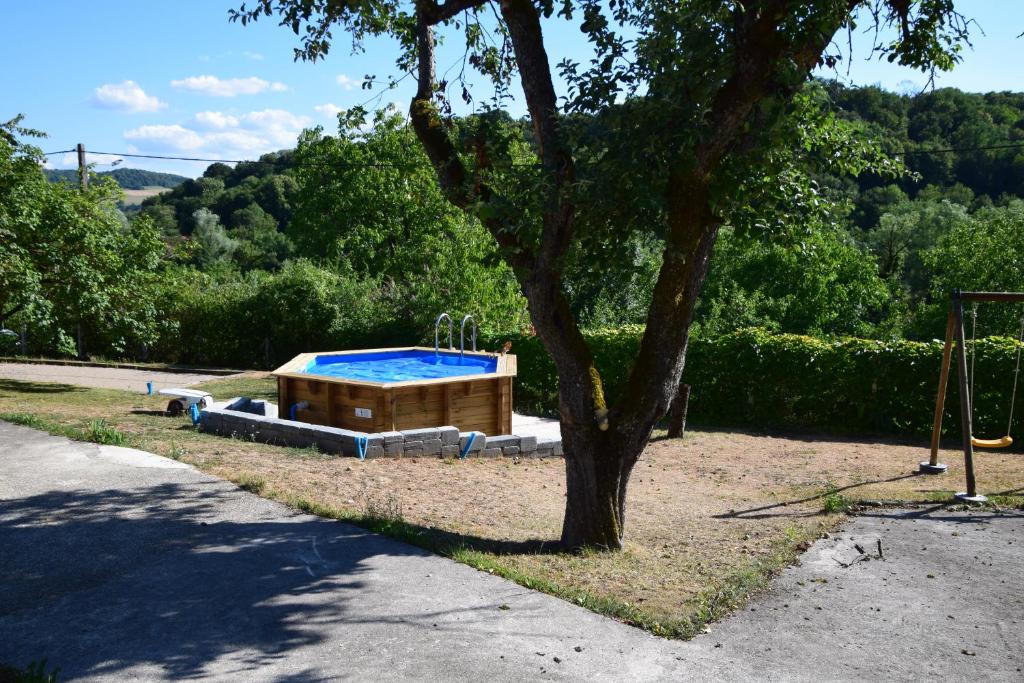 a swimming pool sitting next to a tree at Le Gîte des Petits Cailloux in Vellechevreux-et-Courbenans