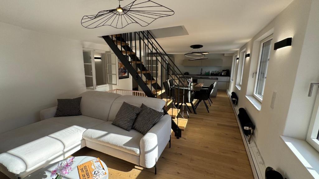 a living room with a white couch and a staircase at Brück Residenz - 100qm Altstadtwohnung an der Steinernen Brücke in Regensburg