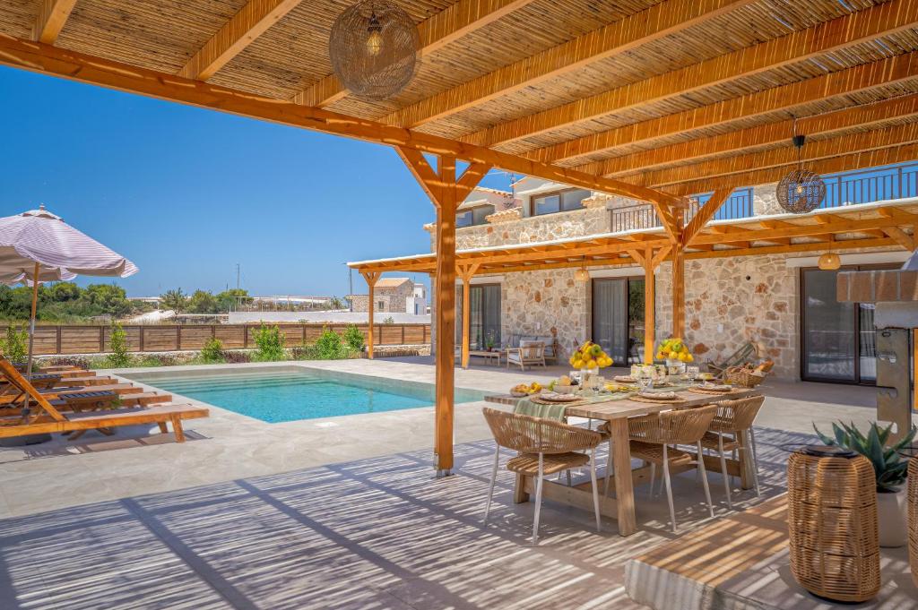 a patio with a table and a swimming pool at Alestone Villa by the sea in Vasilikos