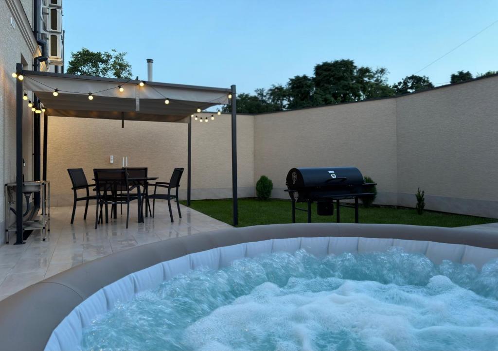 a hot tub in a backyard with a table and a grill at Luxe House Odessa Private Jacuzzi BBQ, Free Parking in Odesa