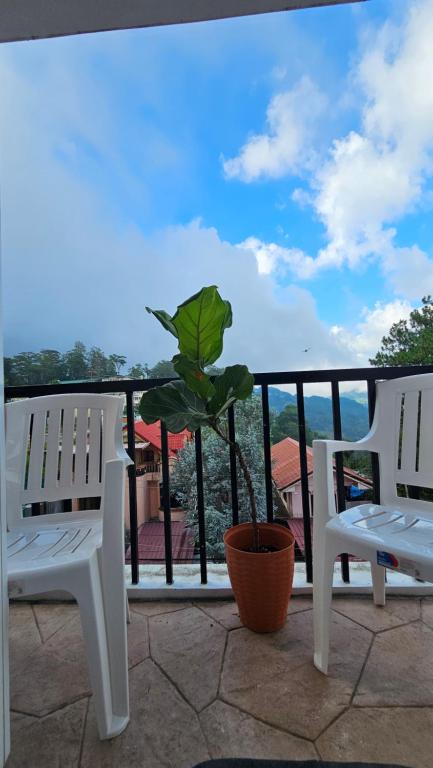 two white chairs and a potted plant on a balcony at VFeel at Home- 2 BR Unit in Baguio