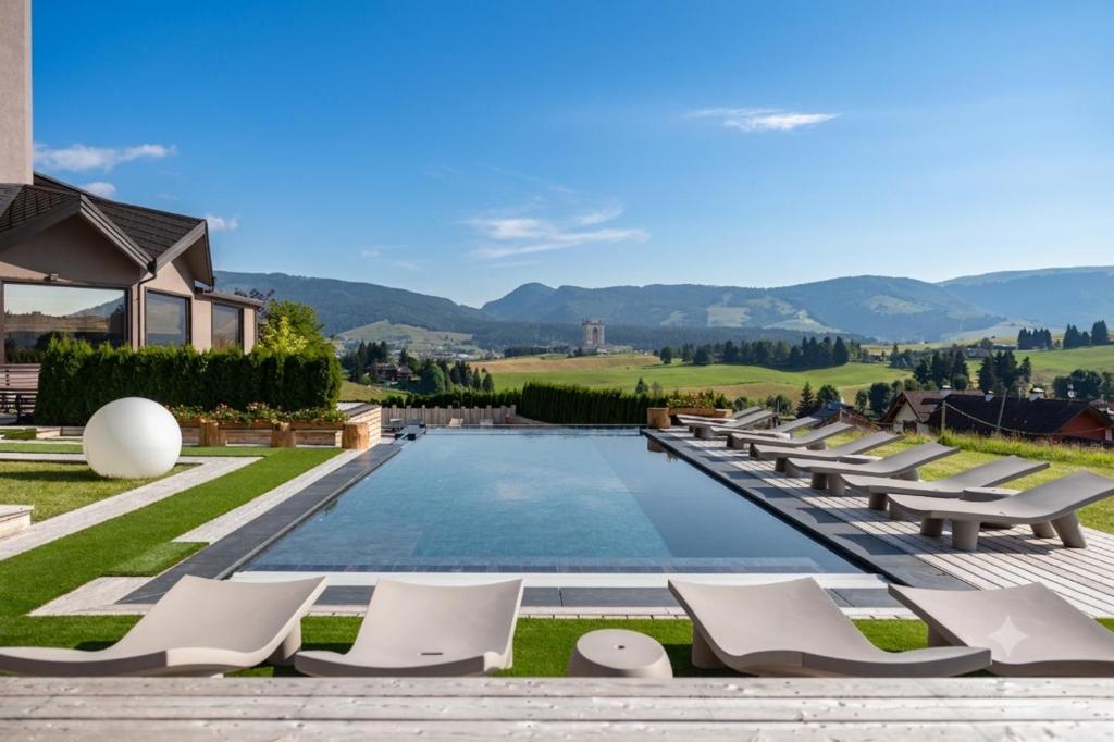 ein Schwimmbad mit Liegestühlen und ein Haus in der Unterkunft Linta Hotel Wellness & Spa in Asiago