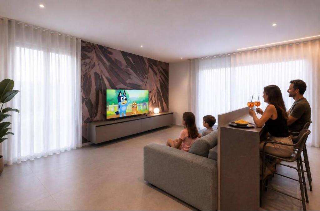 a family sitting in a living room watching tv at A&G Elettra flat a pochi passi dal mare e Venezia in Cavallino-Treporti