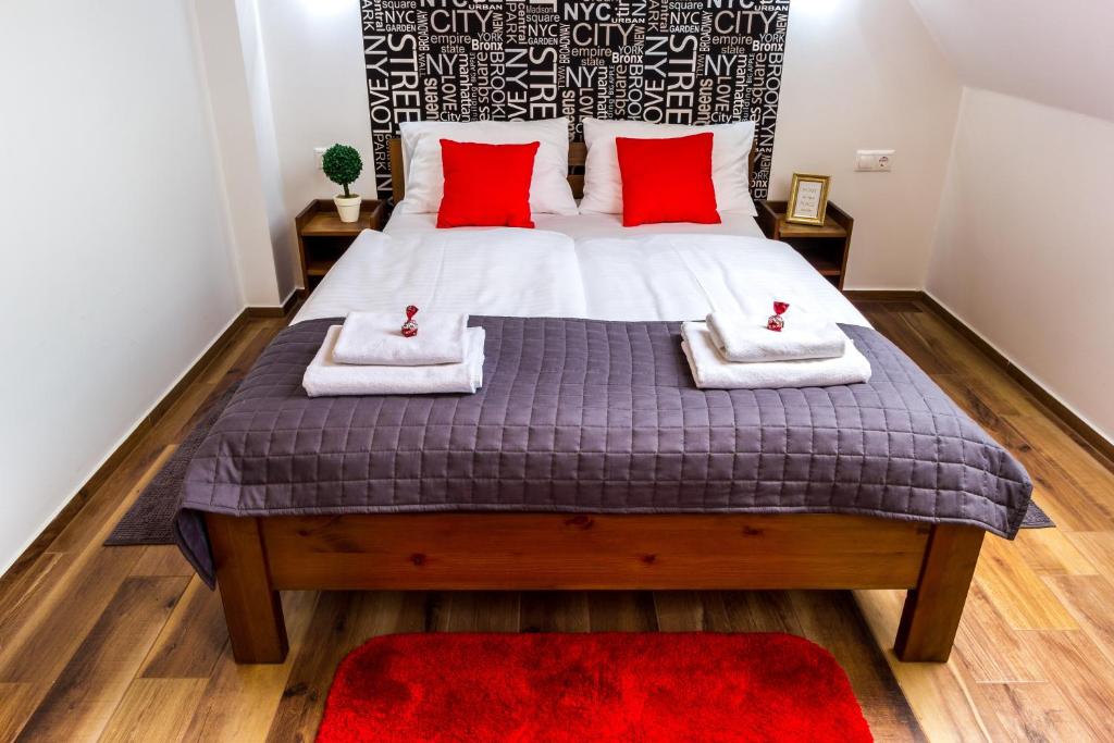 a bedroom with a large bed with red pillows at Aqualiget-Apartmanház in Szeged