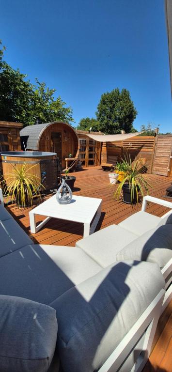a deck with several couches and a table and chairs at L'Esprit Zen #air conditioning #spa in Nercillac