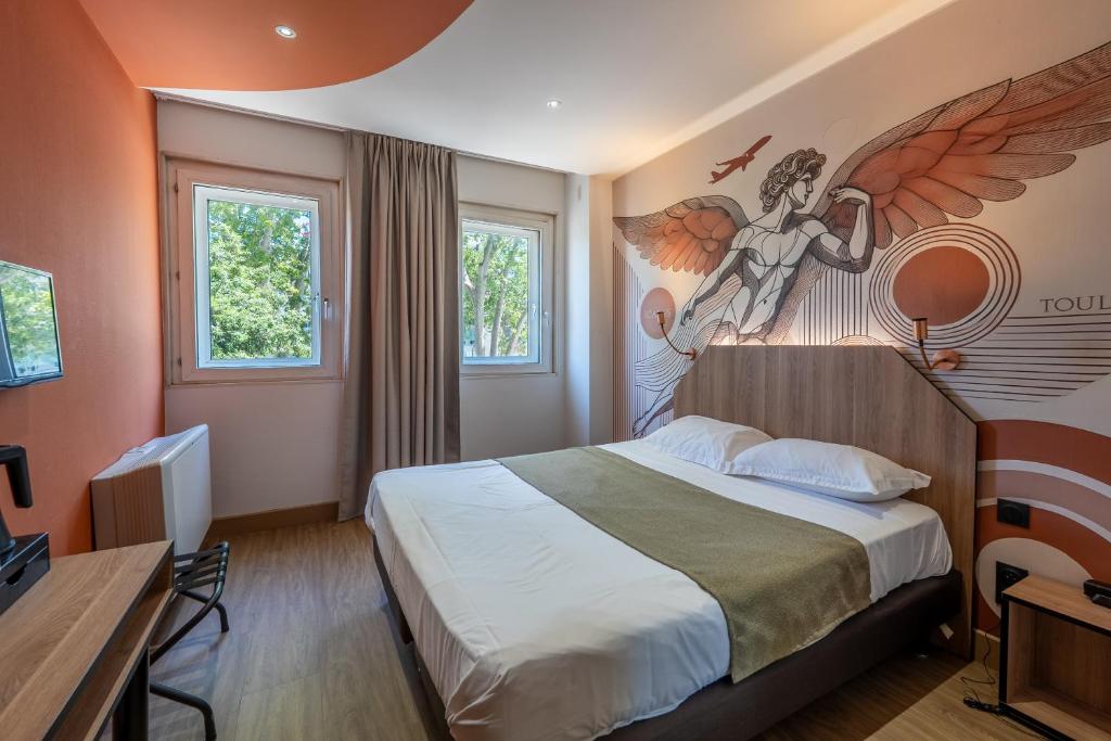 a bedroom with a bed with a painting on the wall at Hôtel Icare in Toulouse