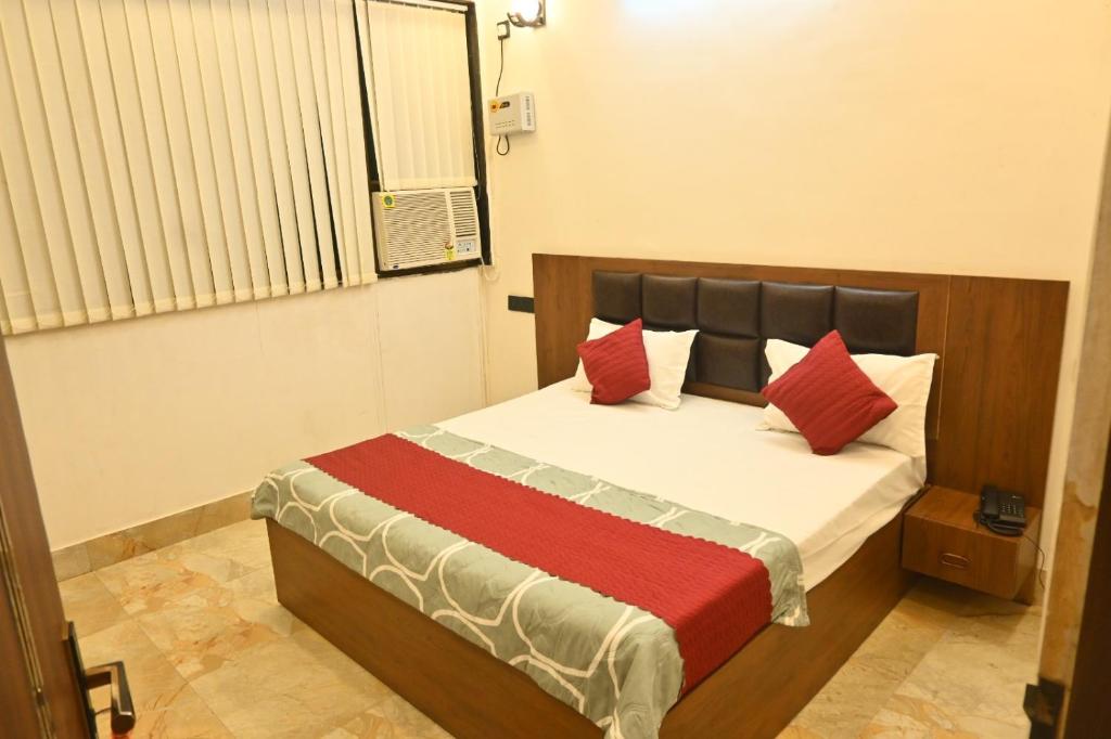 a bedroom with a bed with red pillows at Hotel Shankara Inn in Ayodhya