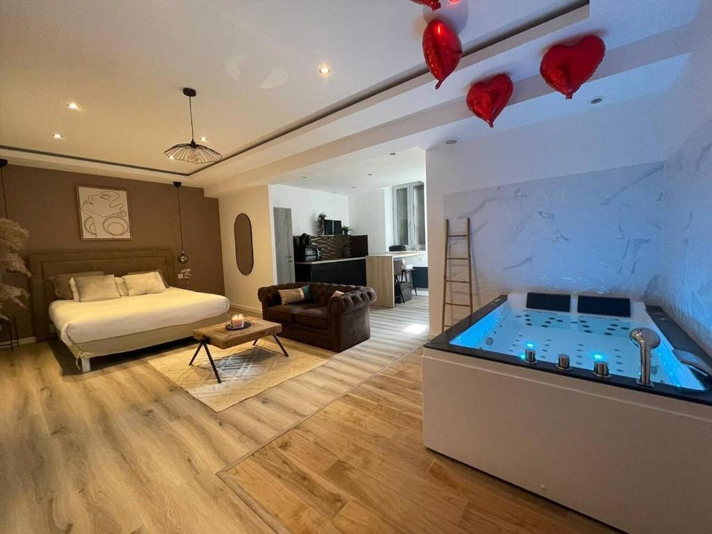 a bedroom with a bed and a tub with hearts on the wall at L'Eden Spa - Jacuzzi - Saint-Etienne in Saint-Étienne