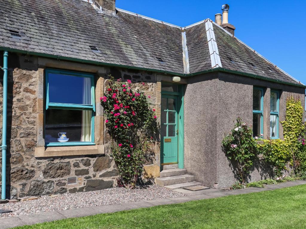 a house with a green door and a cat in a window at Rose Cottage - Uk52178 in Leven