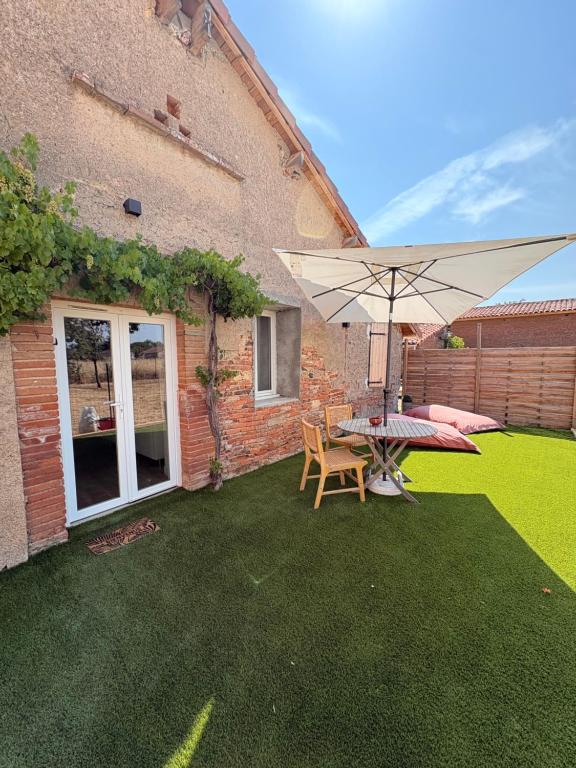 a patio with a table and an umbrella at La parenthèse in Lagrave