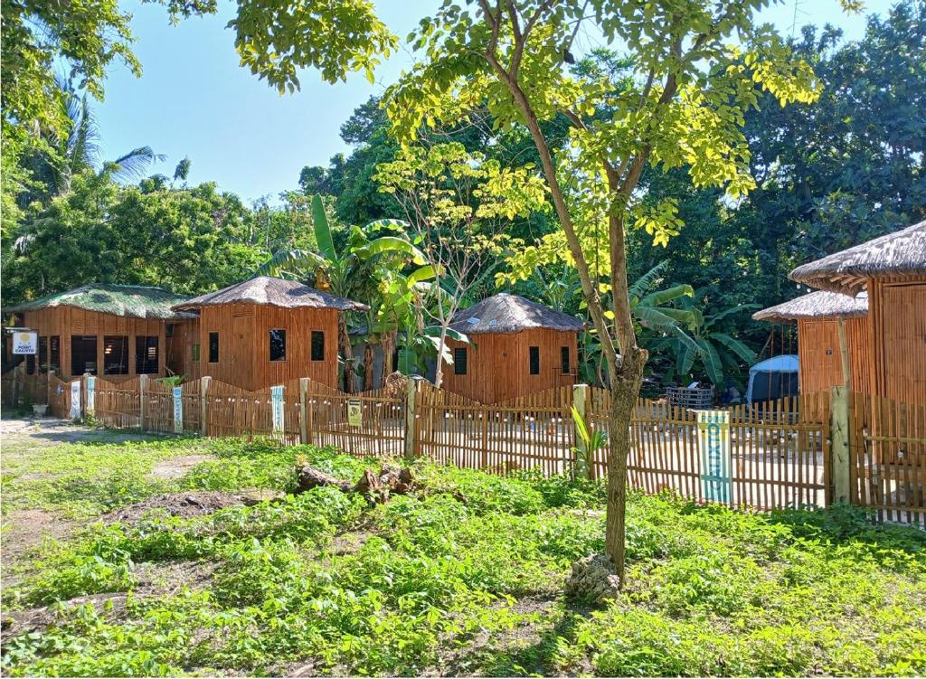 a row of houses with a fence and a tree at Point Calixto beach front hut, Boracay in Boracay