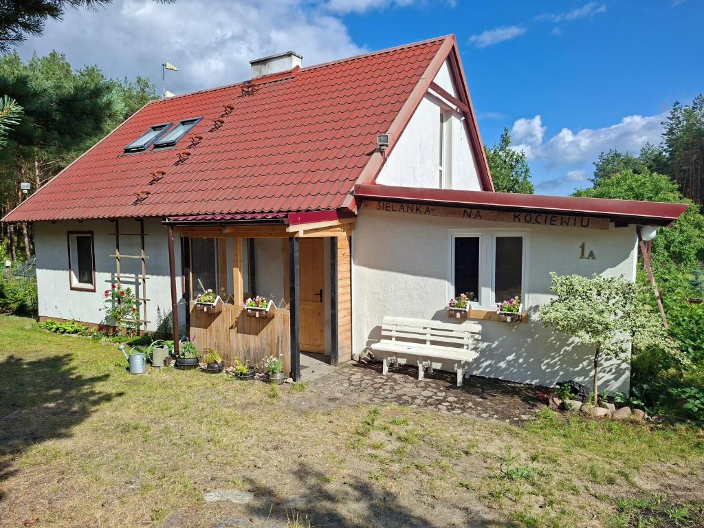 a small white house with a bench in front of it at Sielanka na Kociewiu in Skrzynia