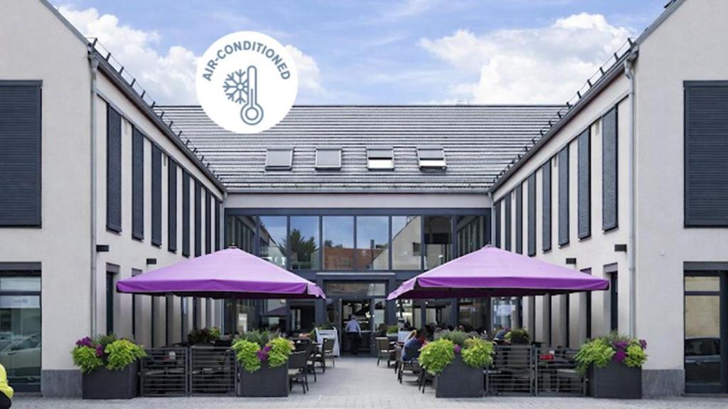 a building with purple umbrellas and tables and chairs at KH Hotel in Geisenfeld