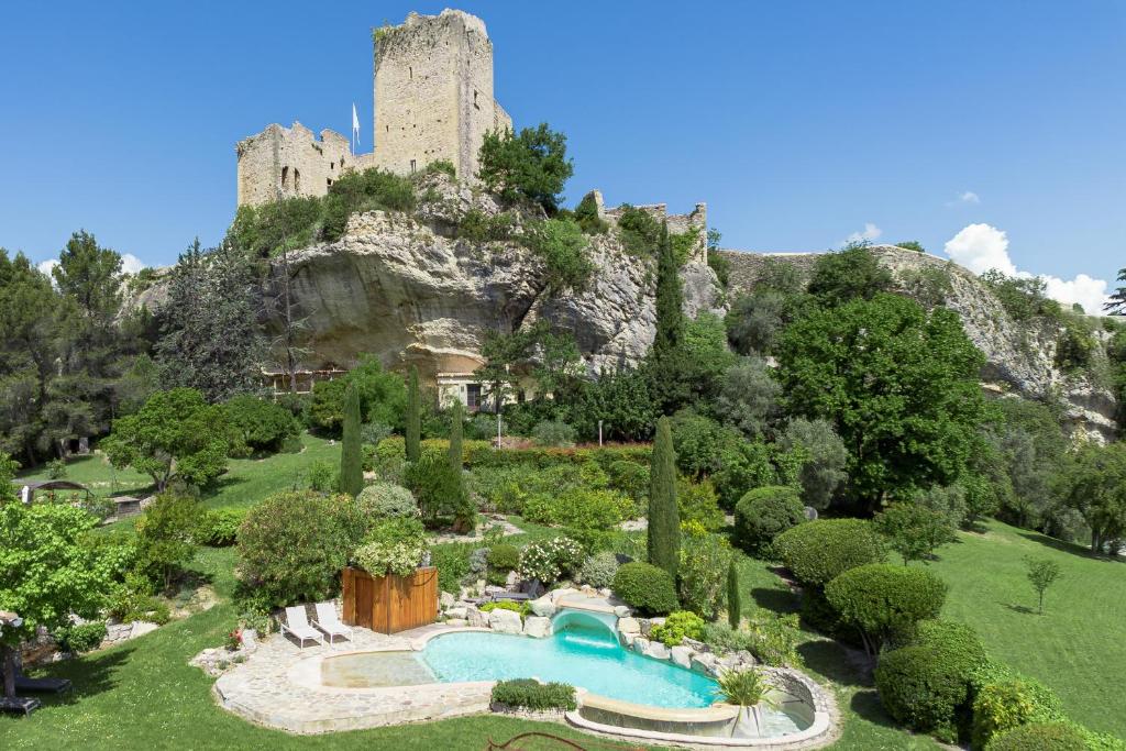 a view of a garden with a castle in the background at La Cascade des Souvenirs Vacation rental just a short walk from Vaison in Vaison-la-Romaine