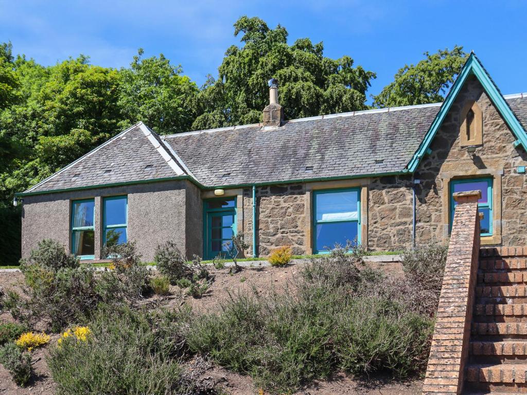 a stone house with blue windows in a garden at Heather Cottage - Uk52177 in Leven