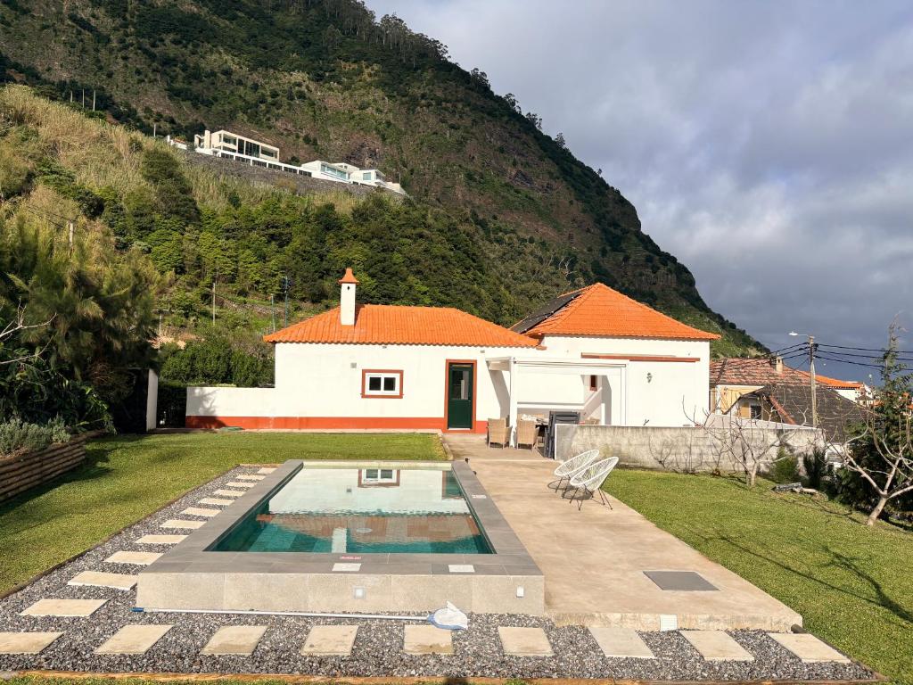 a house with a swimming pool in front of a hill at Casa do Bago in São Vicente