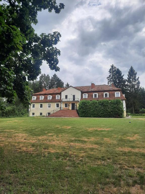 a large house in a field with a grass yard at Dworek kwatery pracownicze in Kętrzyn
