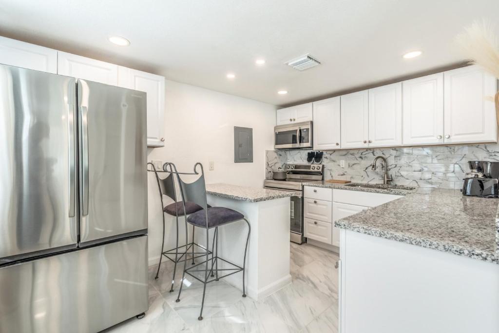 a kitchen with white cabinets and a stainless steel refrigerator at Noel Real Estate in Naples