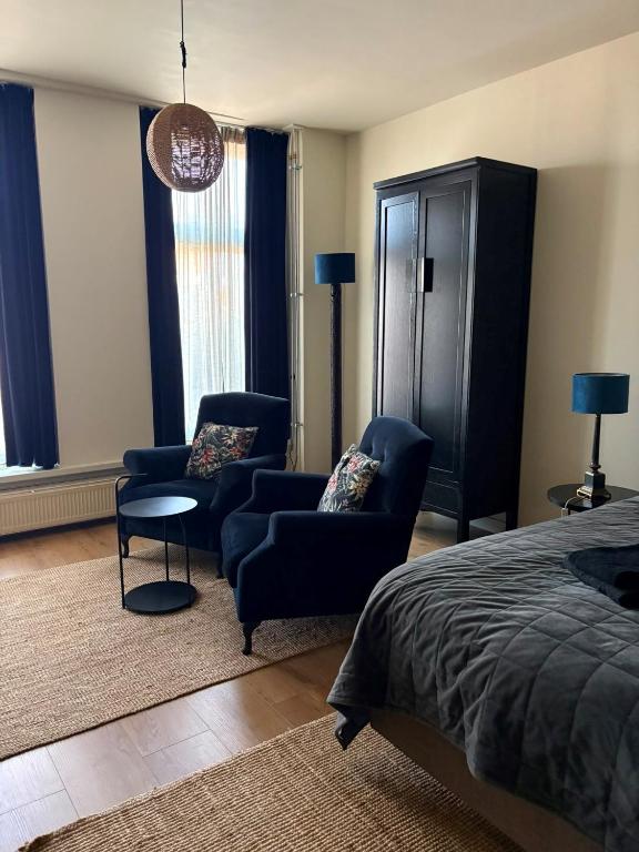 a bedroom with a bed and two chairs and a table at Logement Sylroede in Lemmer